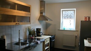 A compact kitchen with a sink, stove, and a window with a view of trees. - A Modern Holiday Home for 2-5 People River Mosel (Moselkern)