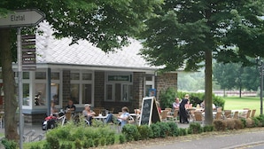 A cafe with outdoor seating, a sign for 'Bitburger', and a 'Café' sign on the building. - A Modern Holiday Home for 2-5 People River Mosel (Moselkern)