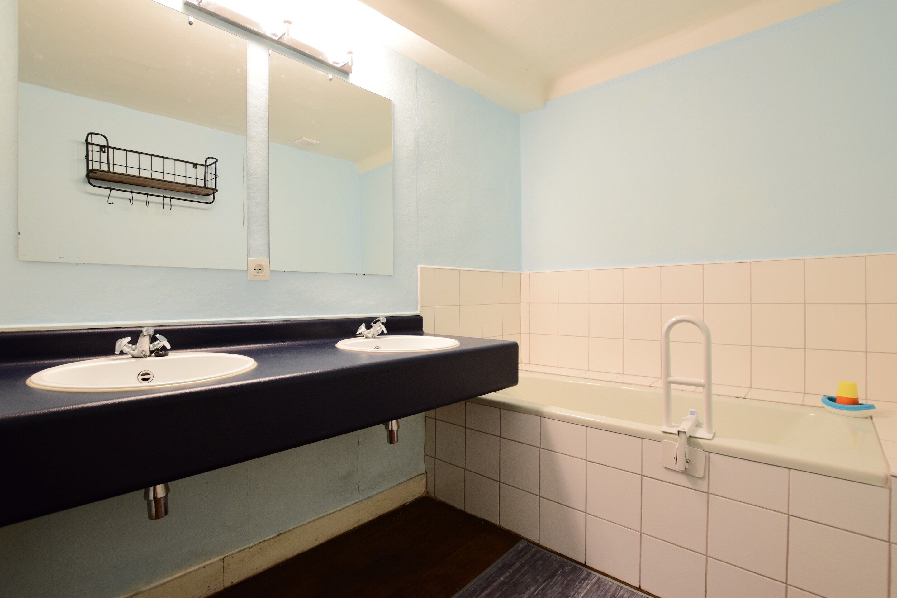 A bathroom with two sinks, a mirror, and a bathtub.