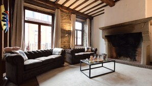 Un salon chaleureux avec une cheminée en pierre, des canapés en cuir et une table basse en verre.