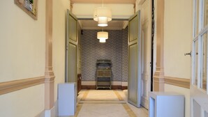 Un couloir avec un mur orné de motifs, une petite armoire et une porte sur le côté droit.