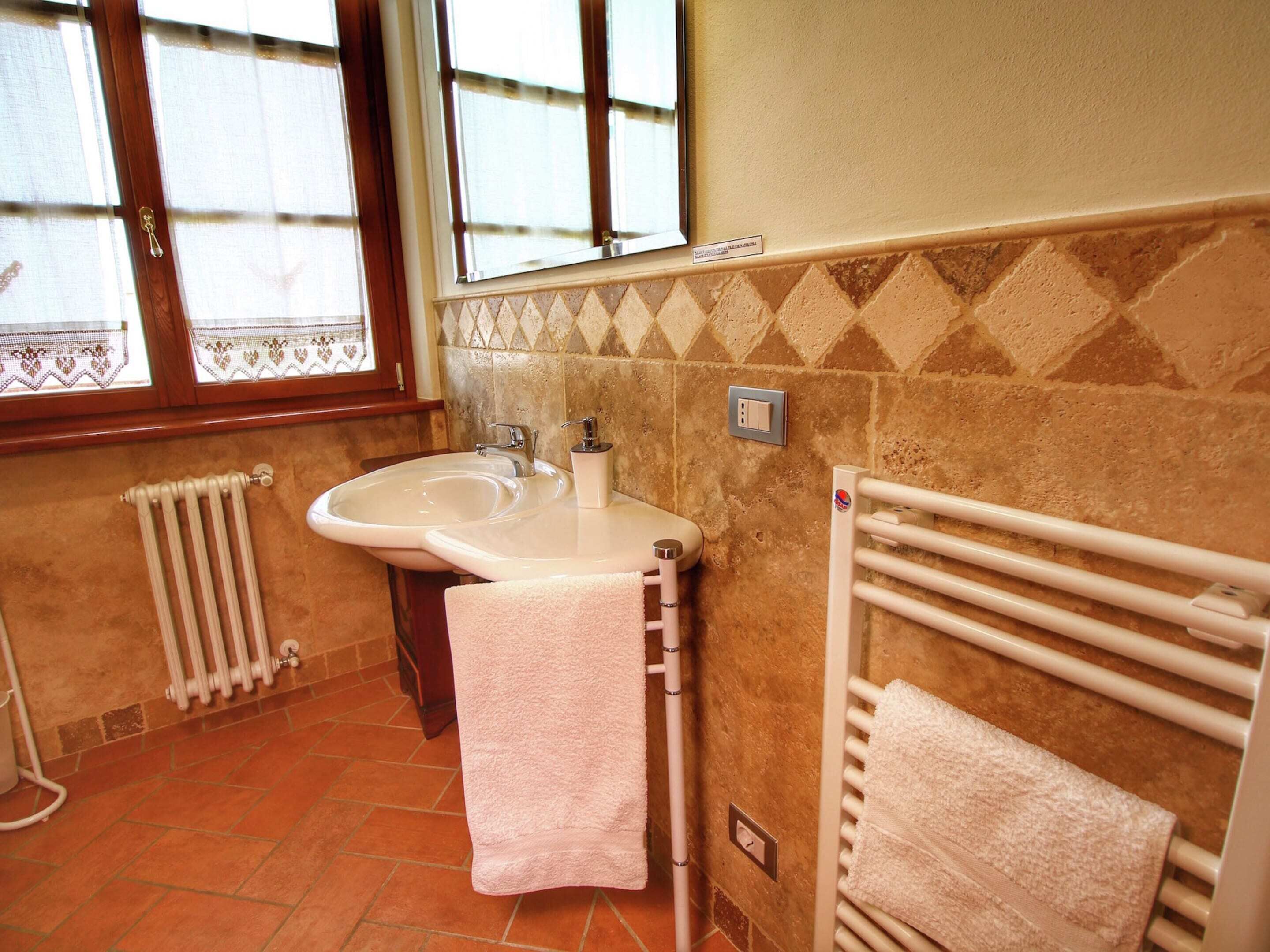 A bathroom with a sink, towel rack, and radiator.