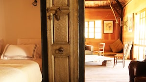 A wooden interior with a bed, a chair, and a door. -  Mimosa chalet Indonésie. (Essaouira)