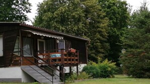 A wooden cabin with a porch and a staircase leading to a deck.