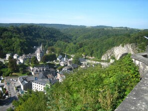 A historic town with medieval architecture, including a castle and church, surrounded by lush greenery and a river. - Holiday Home in Fays With Sauna & Hiking (Manhay)