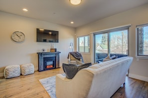 Una sala de estar con chimenea, sofá, televisor y un ventanal grande.