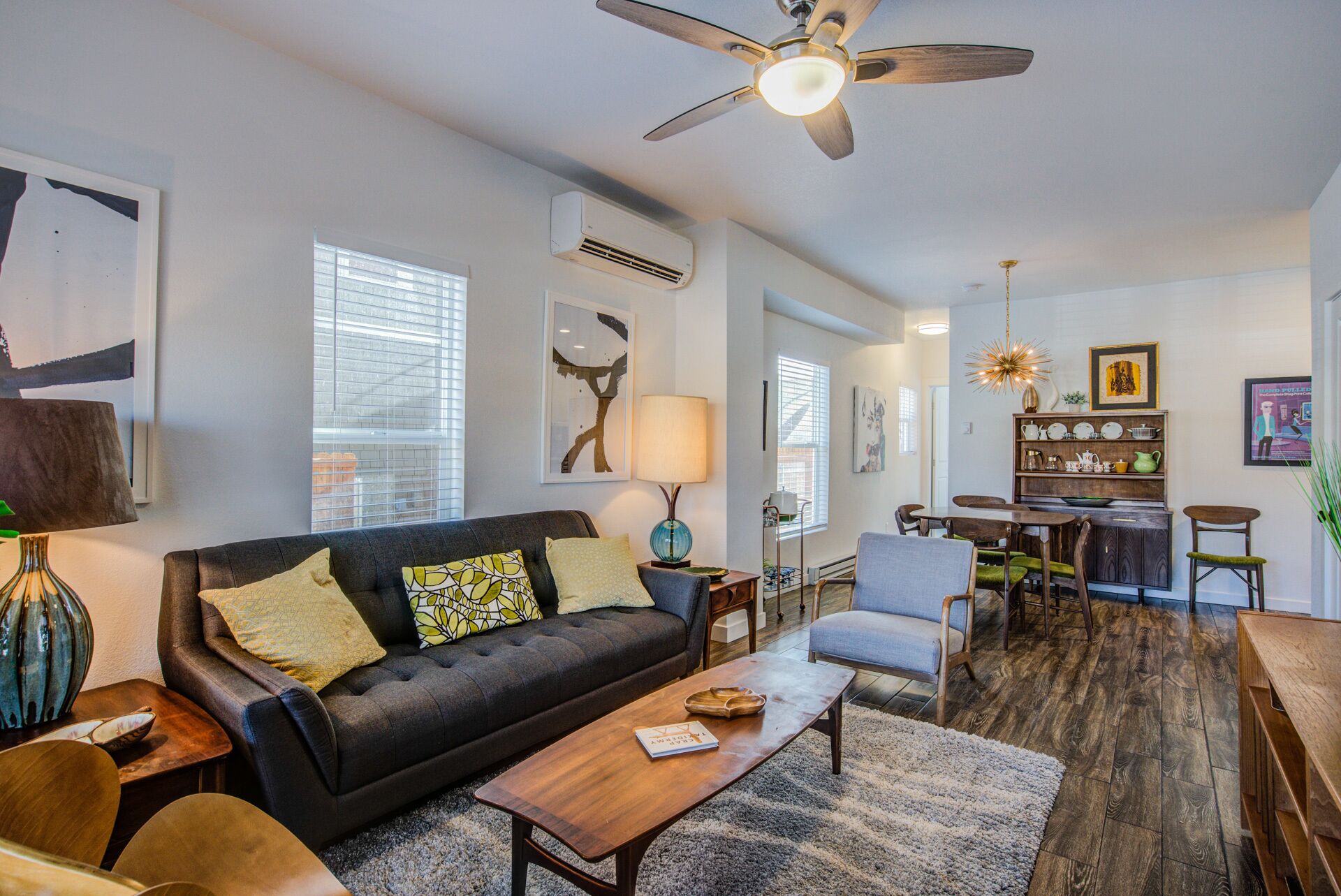 A modern living room with a dark grey sofa, a wooden coffee table, and a ceiling fan.