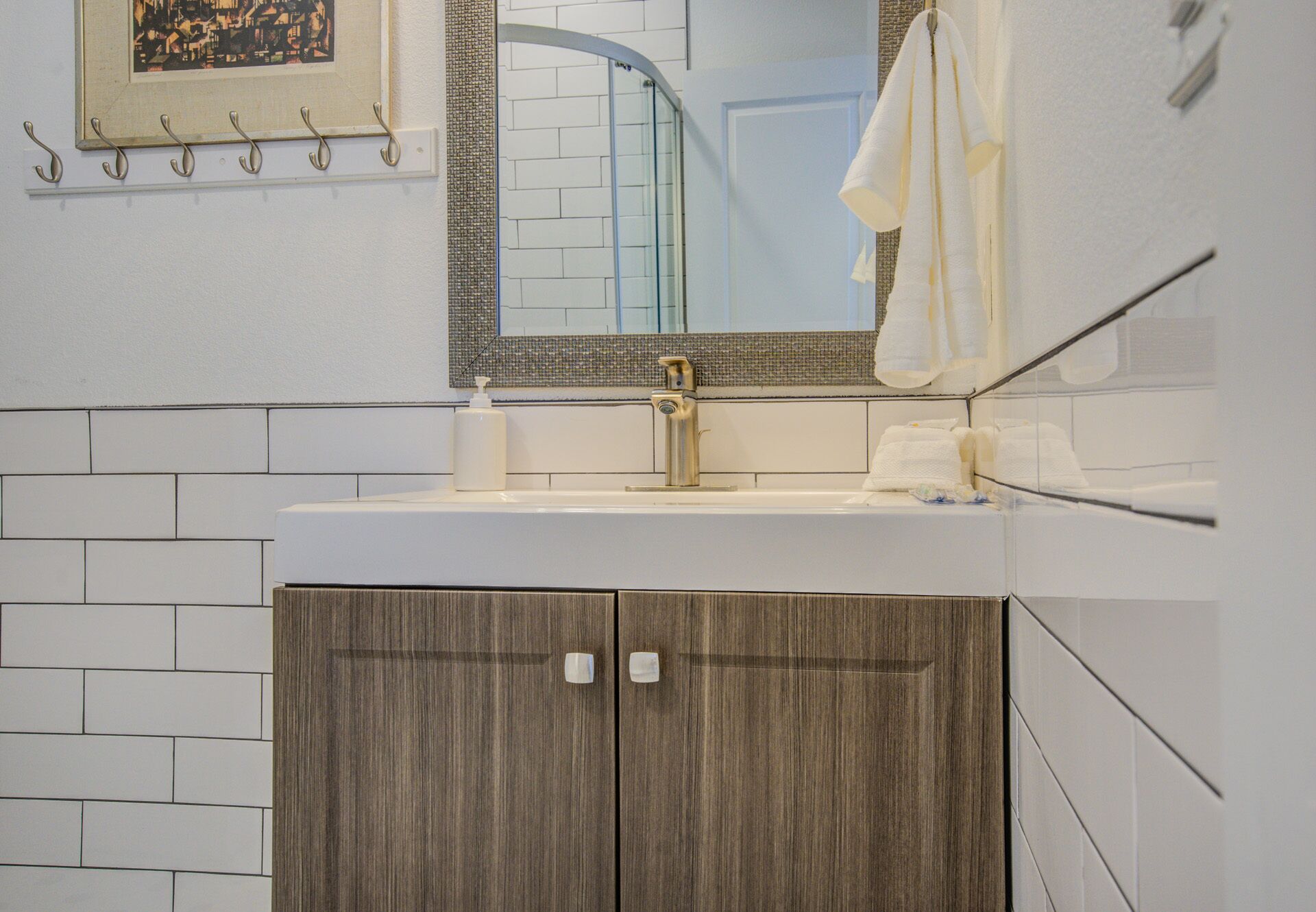 A bathroom with a sink, mirror, towel rack, and wooden cabinet.