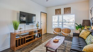 Een woonkamer met een houten tv-meubel, een flatscreen televisie, een wereldbol en twee stoelen.