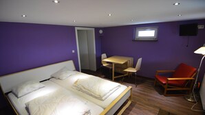 Een slaapkamer met een bed, een bureau, een stoel en een televisie.