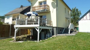 Een huis met twee verdiepingen, een balkon, een schotelantenne en een houten omheining.
