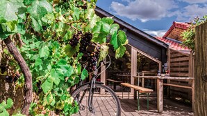 A bicycle parked in a vineyard with a wooden deck and a building in the background. - Fairytale Escape in Lamorteau (Rouvroy)