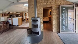 A modern interior with a stone wall, a wood-burning stove, a kitchen with wooden cabinets, and a visible door to another room. - Fairytale Escape in Lamorteau (Rouvroy)