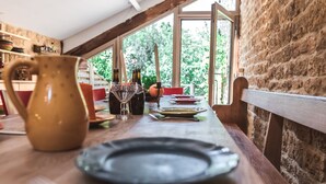 A dining table set with plates, cutlery, and bottles, with a view of greenery outside. - Fairytale Escape in Lamorteau (Rouvroy)