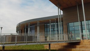 A modern building with a curved facade, large windows, and a pedestrian bridge with metal railings. - Fairytale Escape in Lamorteau (Rouvroy)