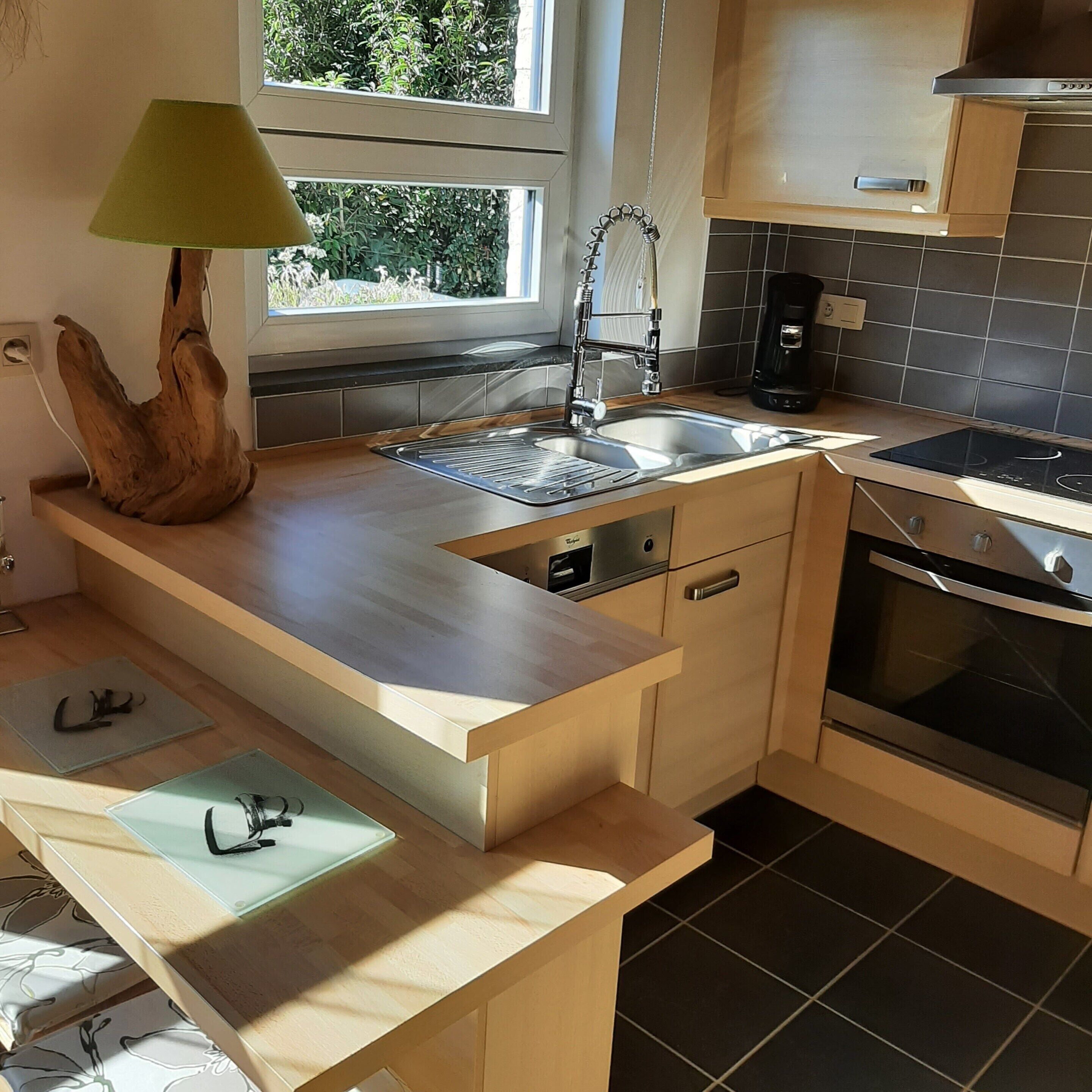 A modern kitchen with a wooden countertop, a sink, a coffee maker, and an oven.