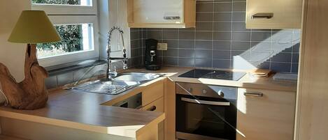 A modern kitchen with a built-in oven, a stove, and a coffee maker.