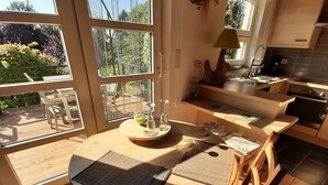 A modern kitchen with large windows, a dining area with a round table, and a view of the garden. - Cottage in Durbuy With Terrace, Garden (Durbuy)