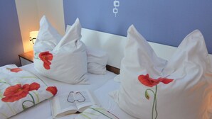 Une chambre d’hôtel avec un lit, des oreillers et un livre ouvert.