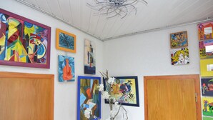 Une pièce dotée d’une porte en bois, d’un ventilateur de plafond et de diverses œuvres d’art accrochées aux murs.
