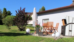 A patio area with a table and chairs, a white umbrella, and decorative spheres. - Ferienhaus in Schwarzhausen (Waltershausen)