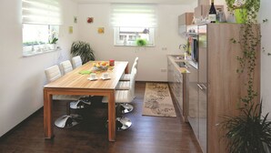 A compact kitchen with a dining area, wooden cabinets, and a refrigerator. - Ferienhaus in Schwarzhausen (Waltershausen)