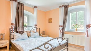 A bedroom with a bed, bedside table, lamp, and window with curtains. - Apartment Nahe Erzgebirge fur 2 Personen (Neuhausen)