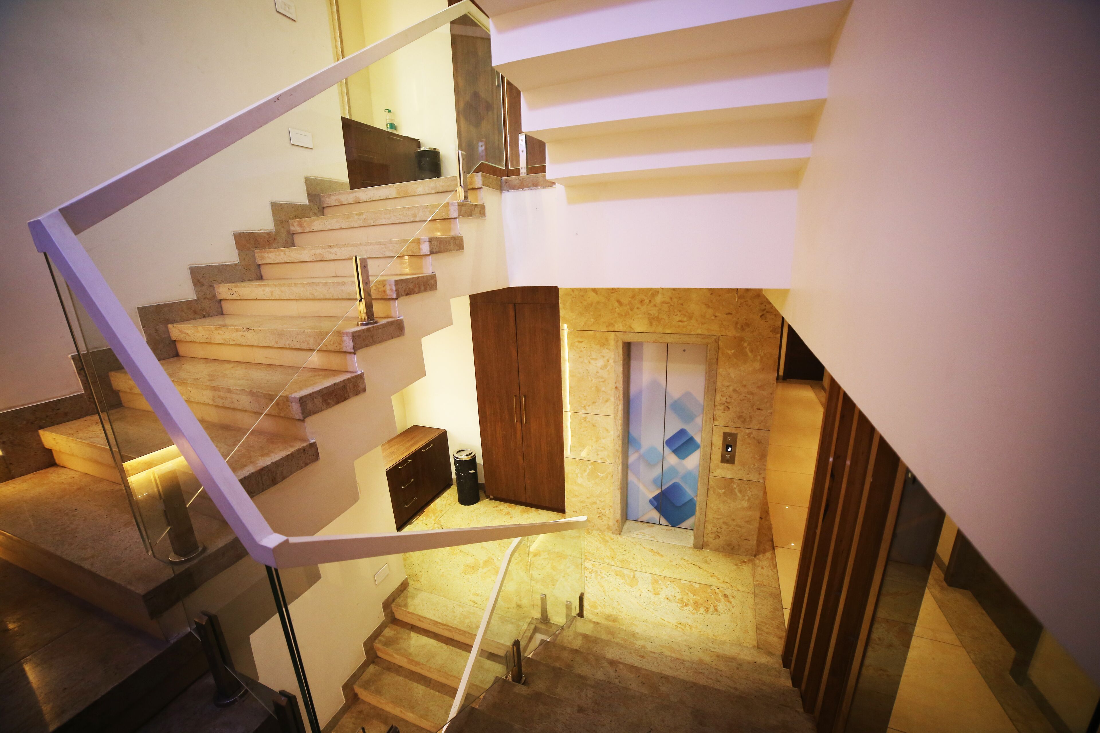 Un escalier moderne avec une rampe en verre et une porte en bois en bas.