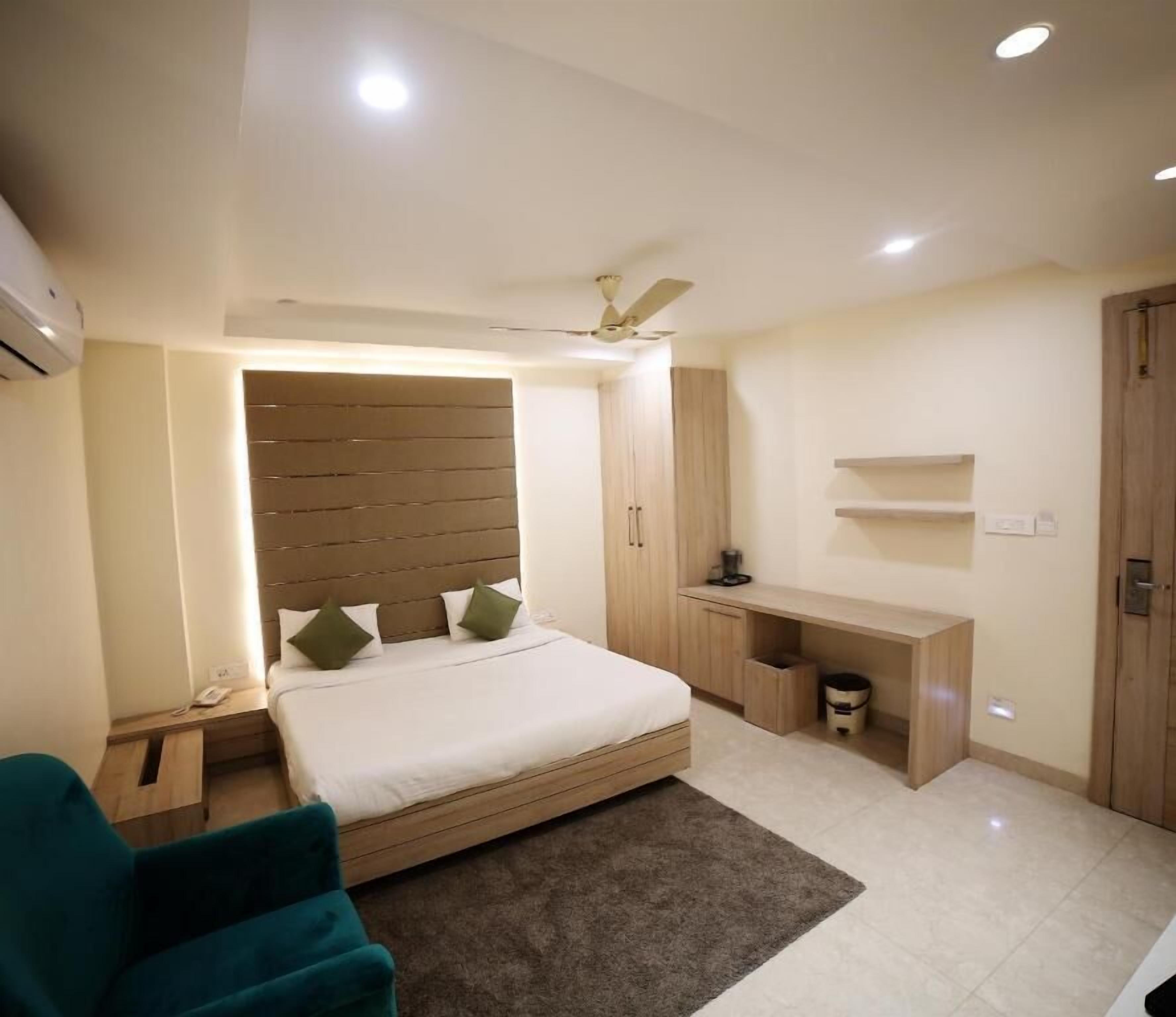 Une chambre à coucher comprenant un lit, un bureau, une chaise, un ventilateur de plafond et une armoire.