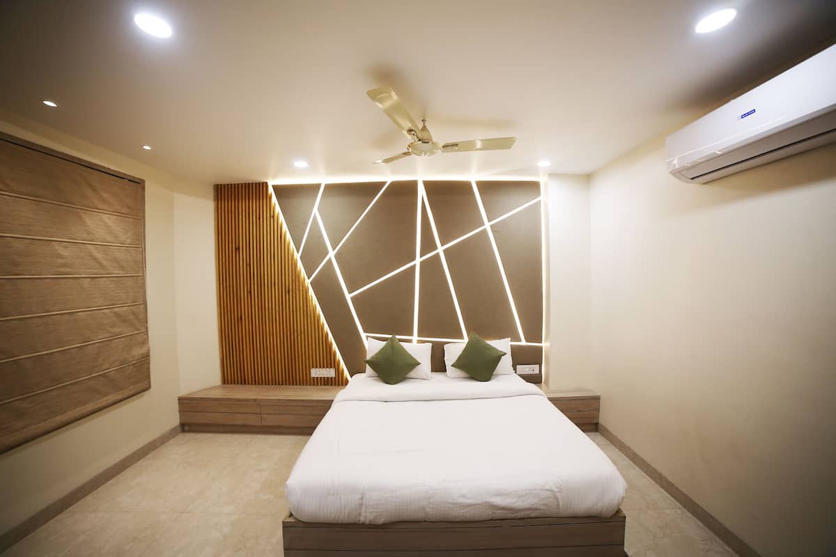 Une chambre à coucher comprenant un lit, un ventilateur de plafond, un éclairage encastré, une tête de lit en bois et un appareil de climatisation.