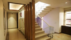 A staircase with wooden handrails and a glass barrier, leading to a landing with a fire extinguisher.