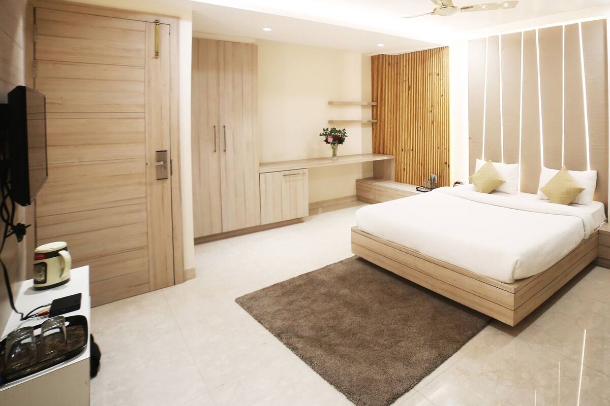 Une chambre moderne avec un lit, un téléviseur, un ventilateur de plafond et un lambris en bois.