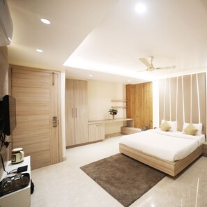 A modern bedroom with a bed, wooden wardrobe, and a ceiling fan. - Hotel Avantika  (Bhopal)