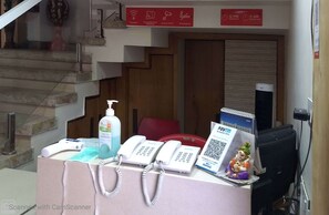 A reception desk with a phone, a Paytm sign, a small statue, and a sign indicating check-in and check-out times. - Hotel Avantika  (Bhopal)