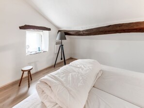 Cozy loft-style room with a single bed, wooden stool, and floor lamp.