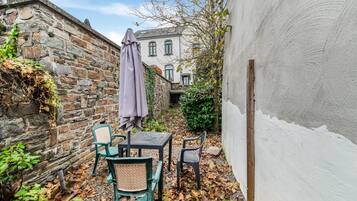 Un patio con muros de piedra, un edificio blanco y dos sillas al aire libre.