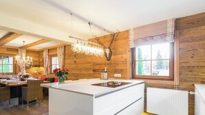 A modern kitchen with a central island, wooden walls, and large windows.