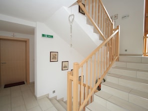 Stairs lead to an upper floor with framed pictures and a door.