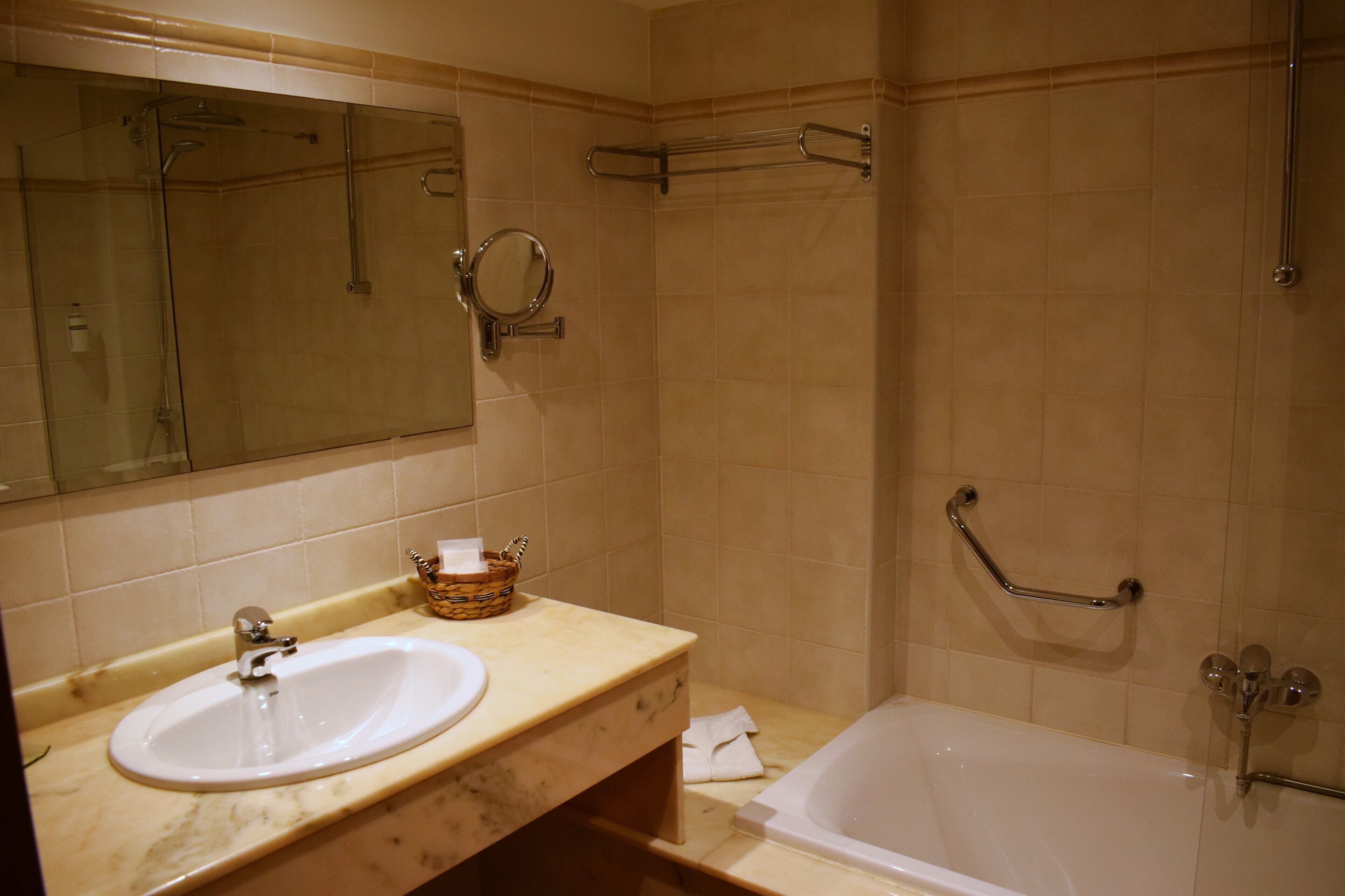 A bathroom with a sink, mirror, and bathtub.