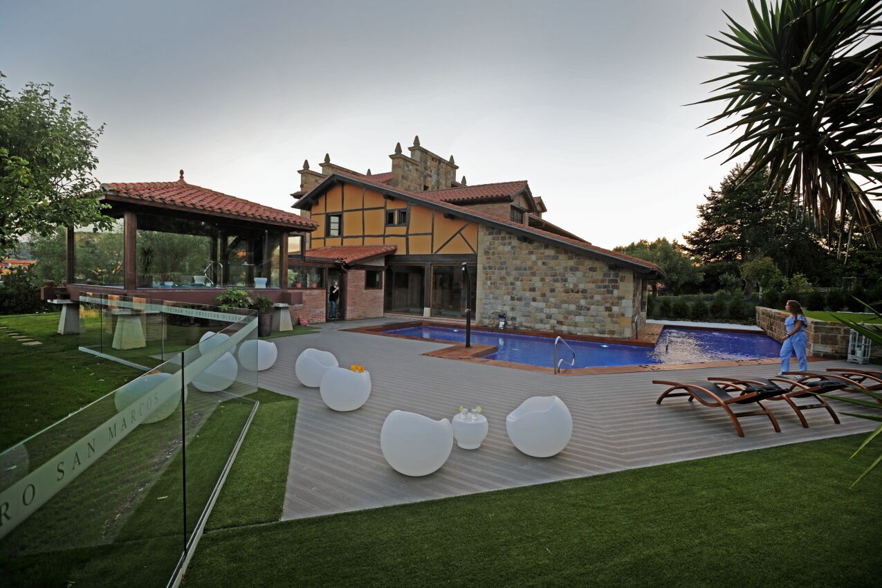 A modern house with a swimming pool, outdoor seating, and a well-maintained garden.