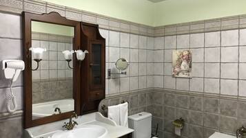 Un baño con lavamanos, espejo, tocador, inodoro y bidé.