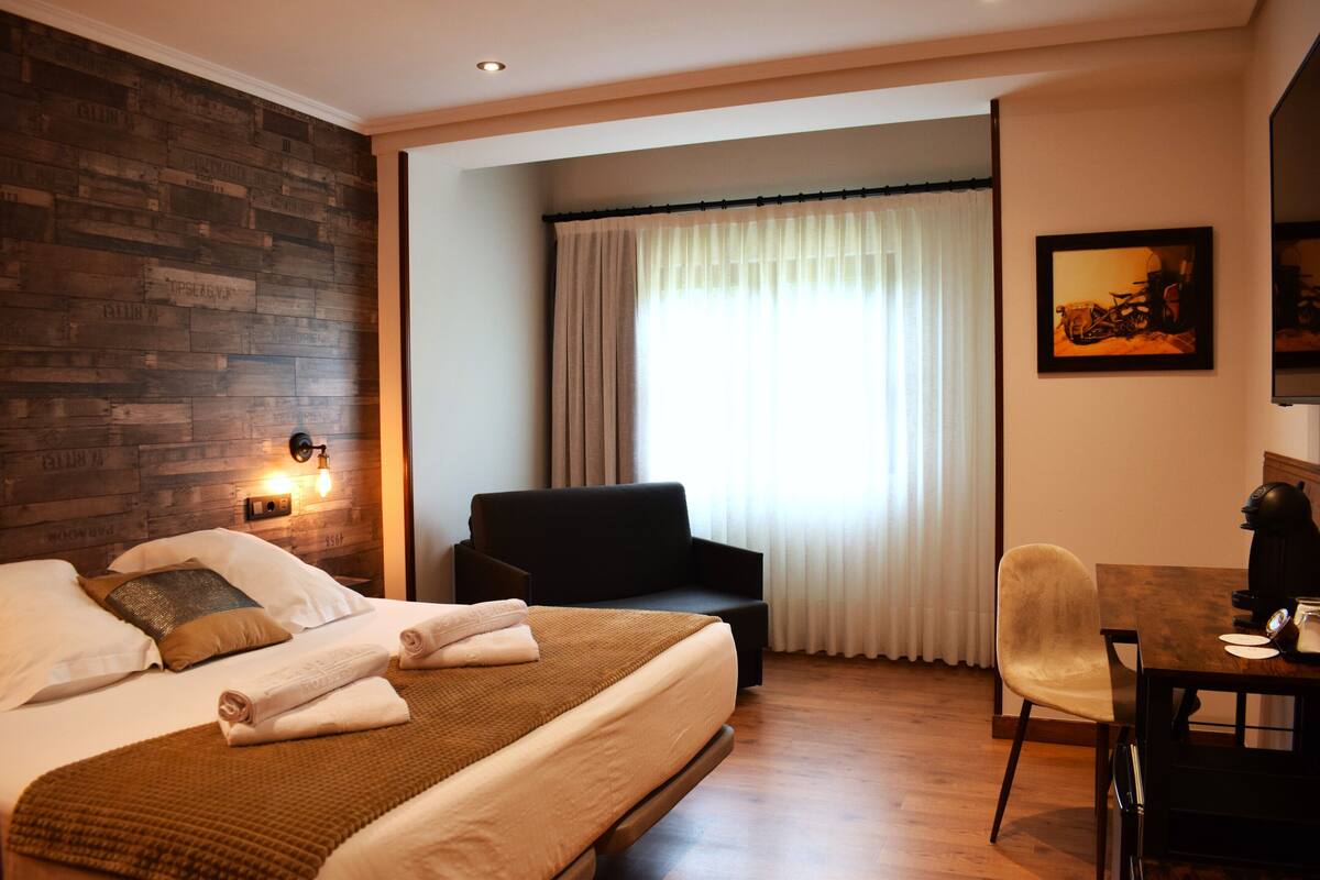 Une chambre d’hôtel avec un lit, un canapé, une table à manger et une chaise.