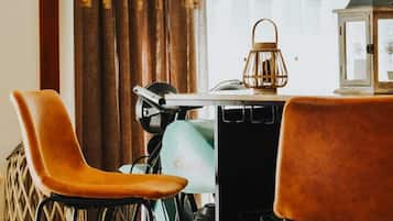 Una habitación con una mesa de comedor, dos sillas, una bicicleta, un farol y una ventana con cortinas.