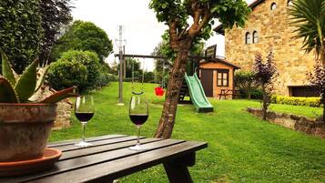 A patio with a table, two glasses of red wine, and a potted plant.