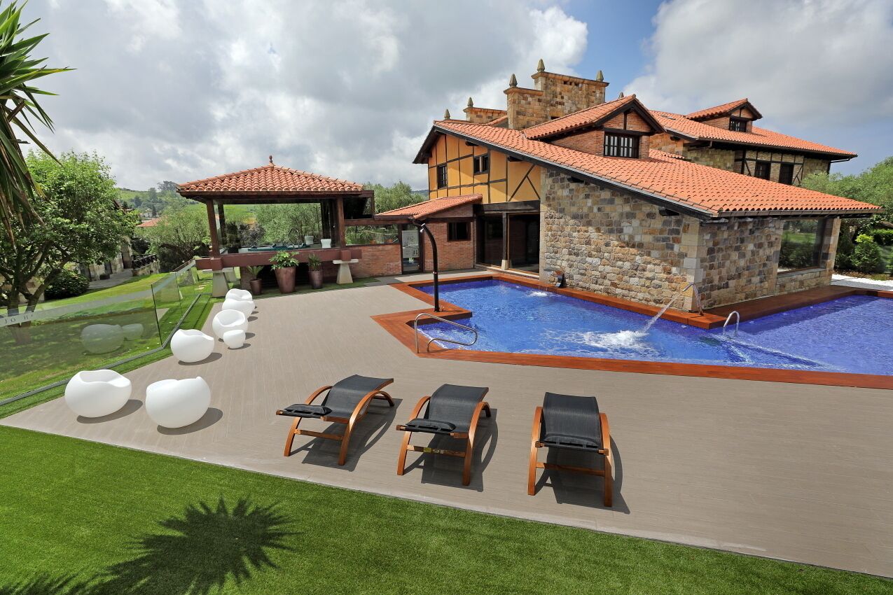 A modern villa with a swimming pool, outdoor seating, and a stone facade.