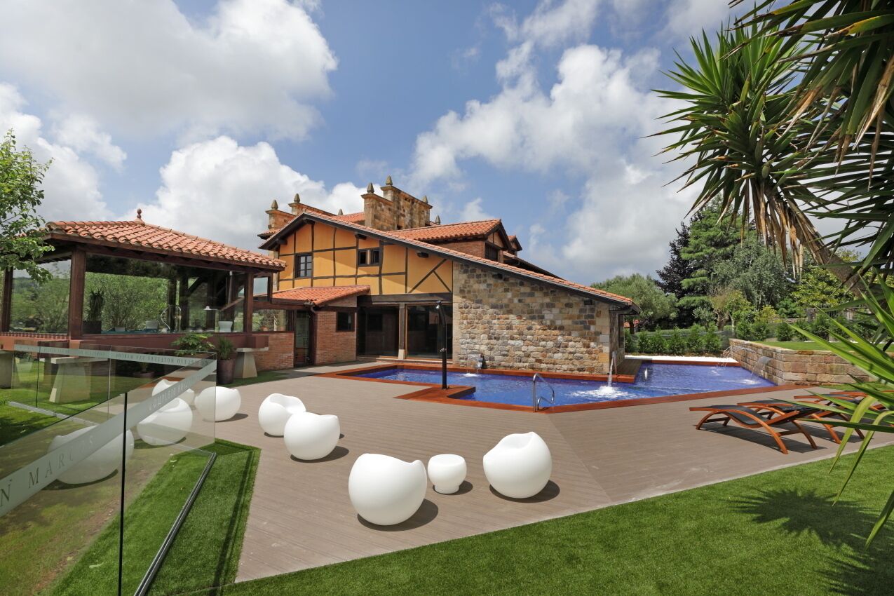 Una casa moderna con piscina, mobiliario exterior y un jardín bien cuidado.