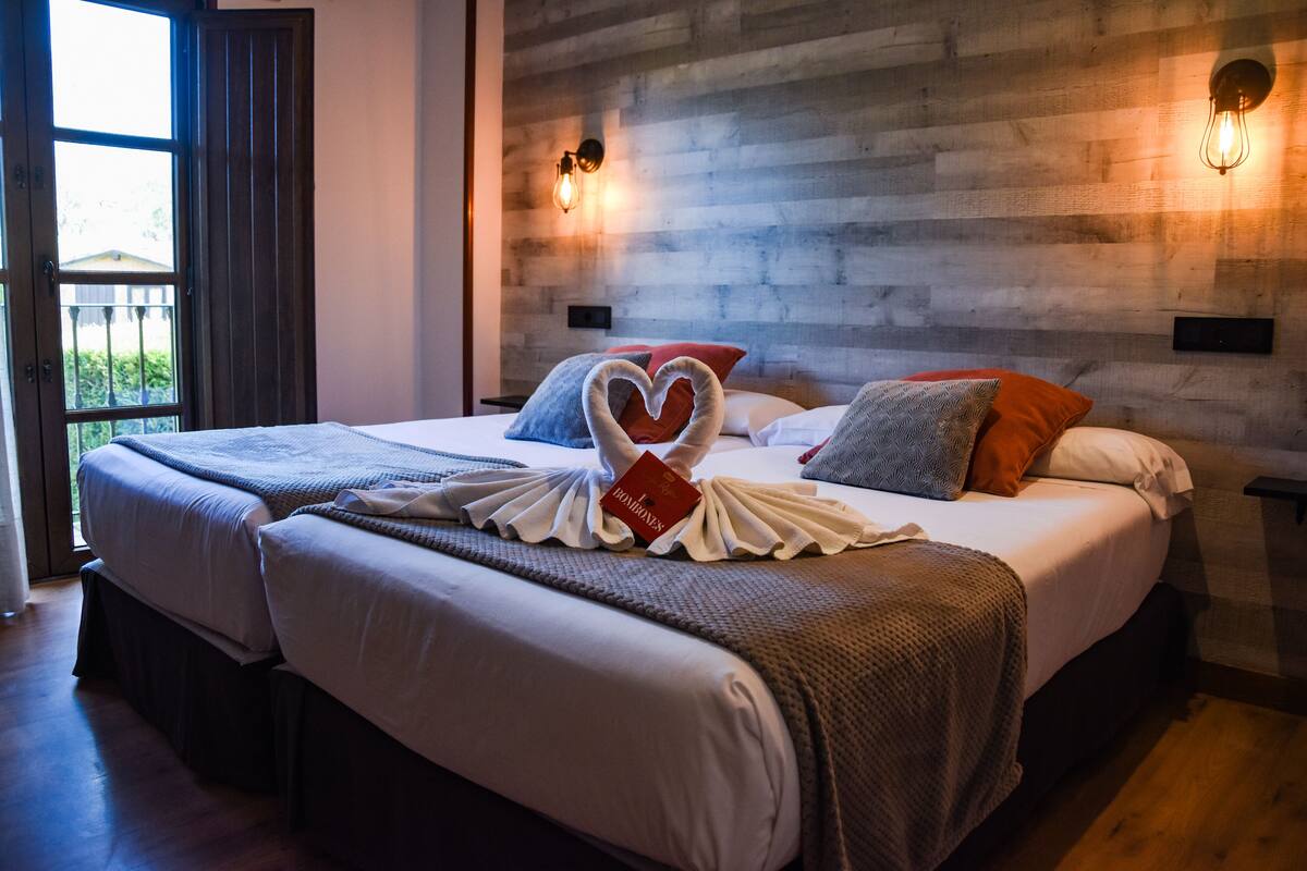 Une chambre d’hôtel avec deux lits, un mur en bois et une fenêtre donnant sur un paysage agréable.