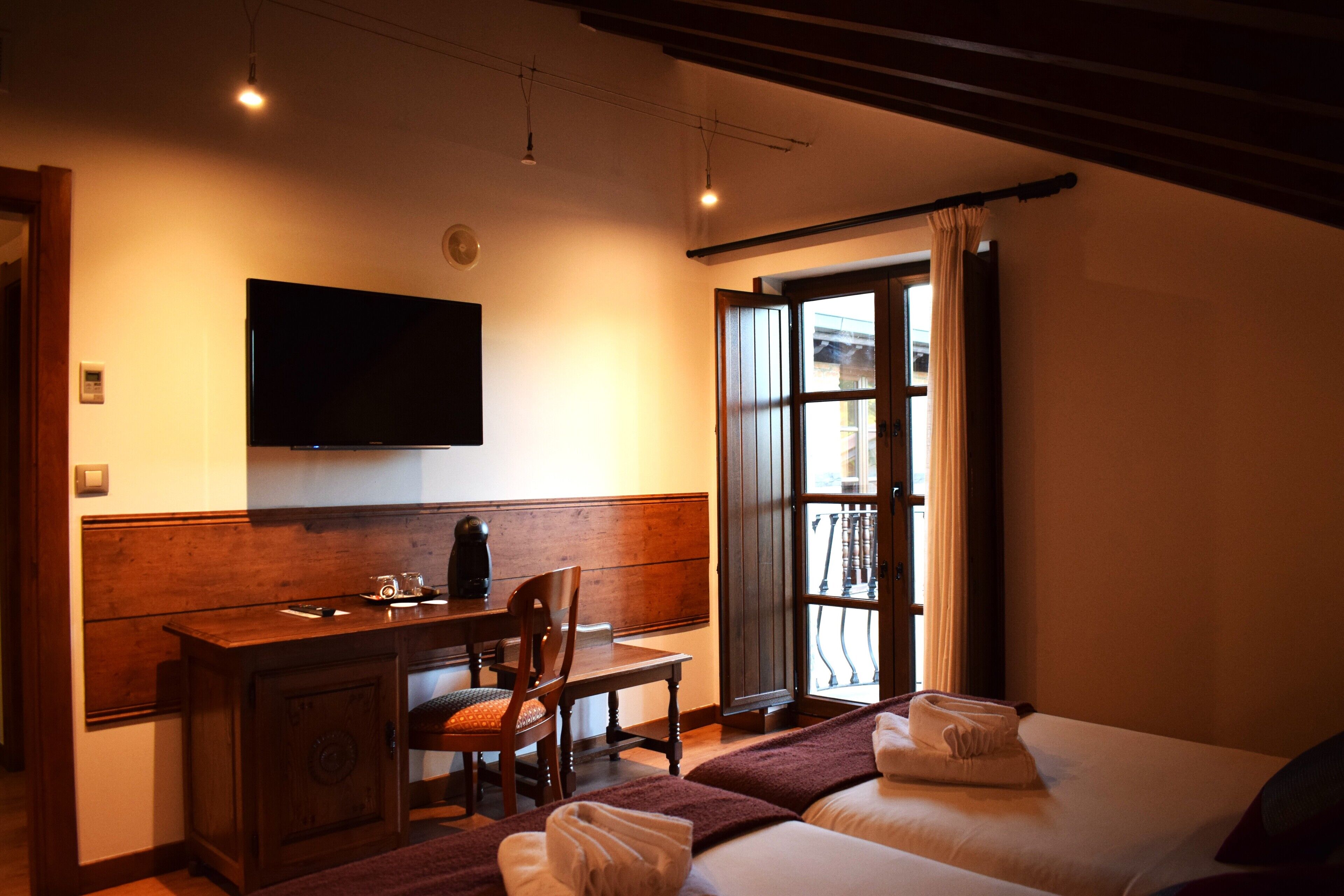 A hotel room with a bed, a desk, a chair, a television, and a window with curtains.
