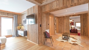 A room with wooden walls, a flat-screen TV, a desk, a chair, a table, and a cowhide rug. - Unique Chalet in the Center of Elmau Near the Ski Lift (Ellmau)