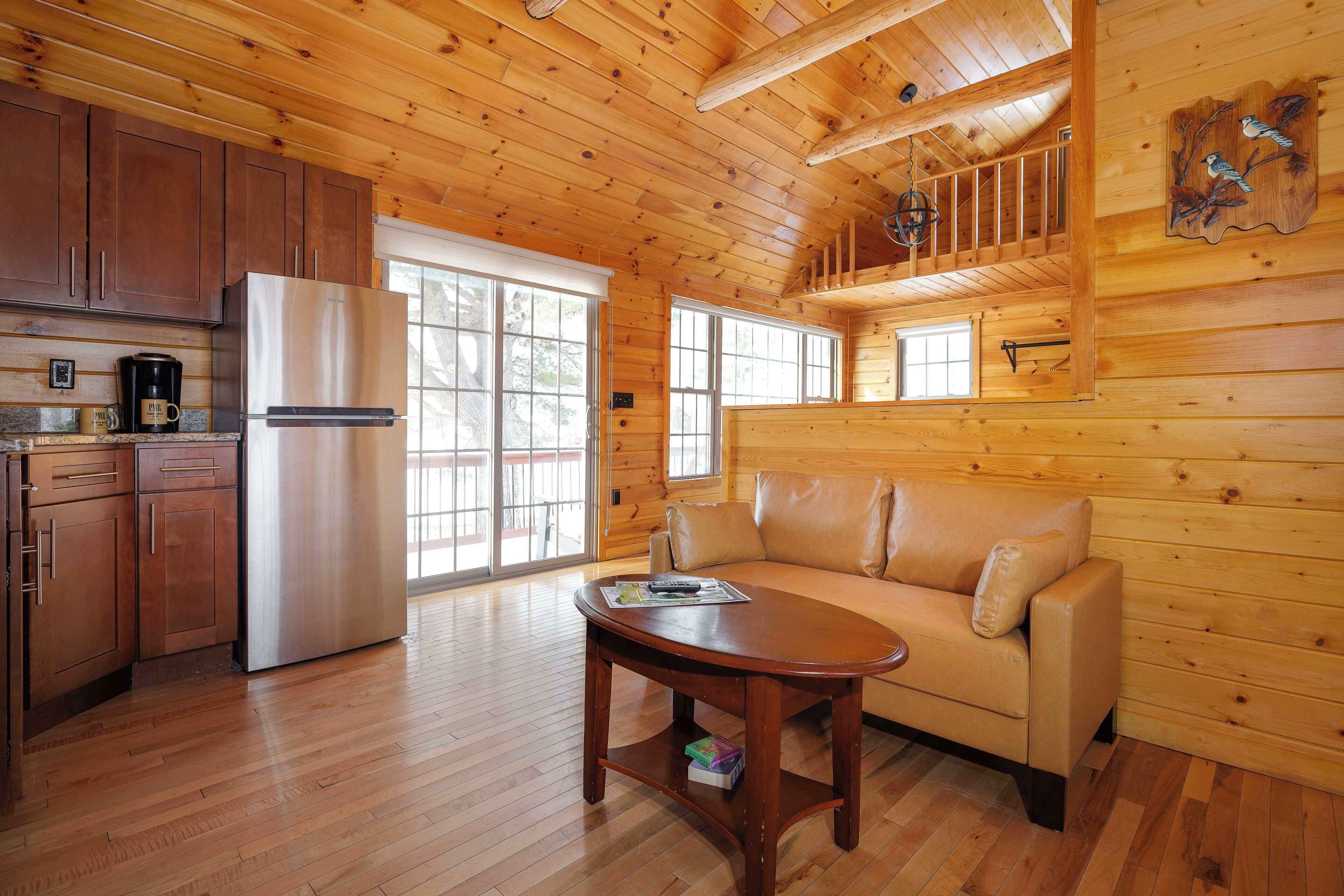 Interior de una cabaña de madera con cocina, un sofá y una mesa de comedor.